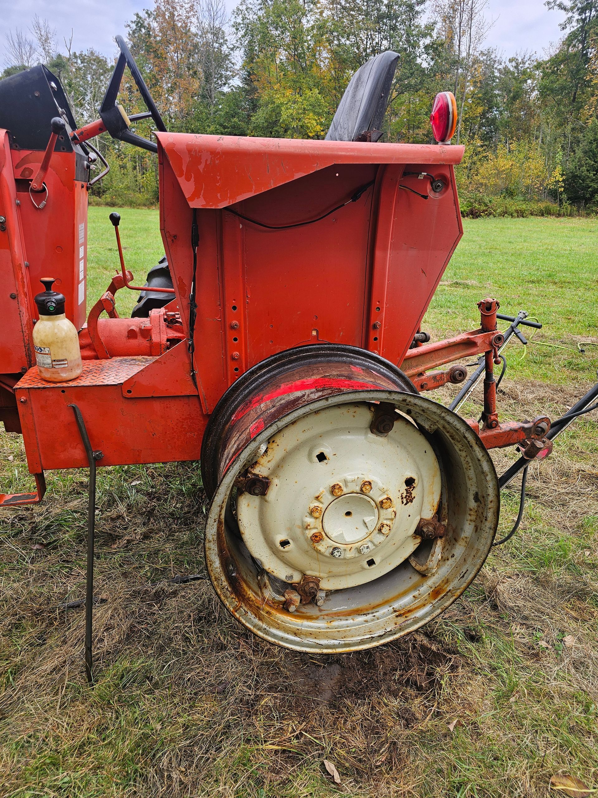 An old red tractor is parked in a grassy field.