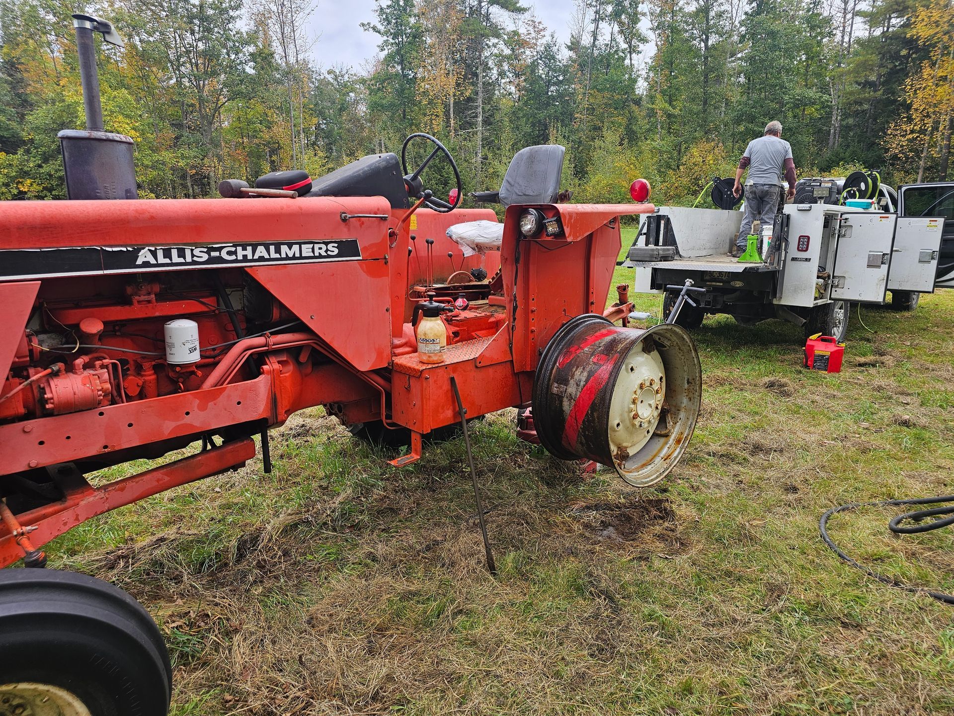 A man is working on a tractor in a field.