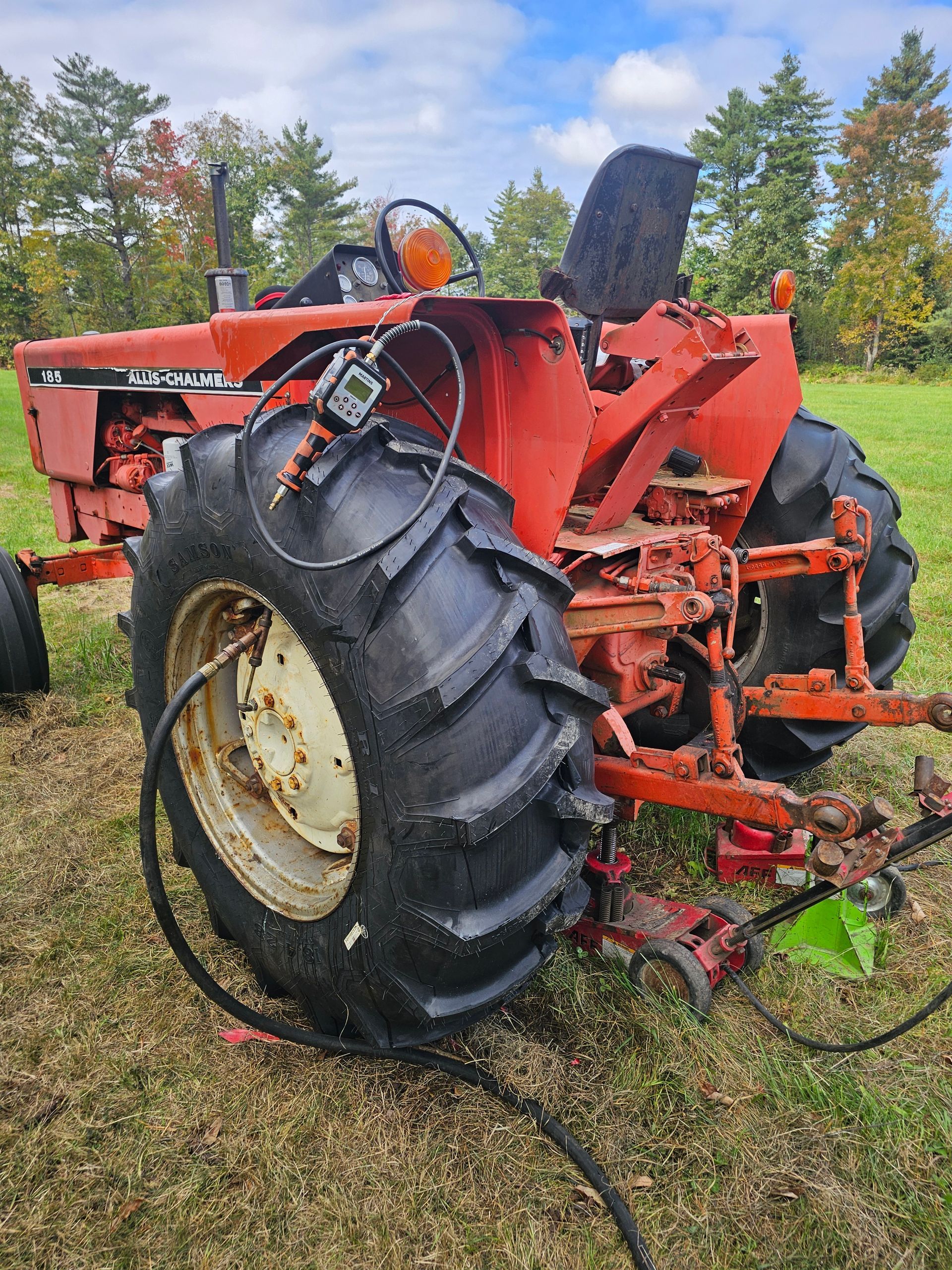 A red tractor is parked in a grassy field.
