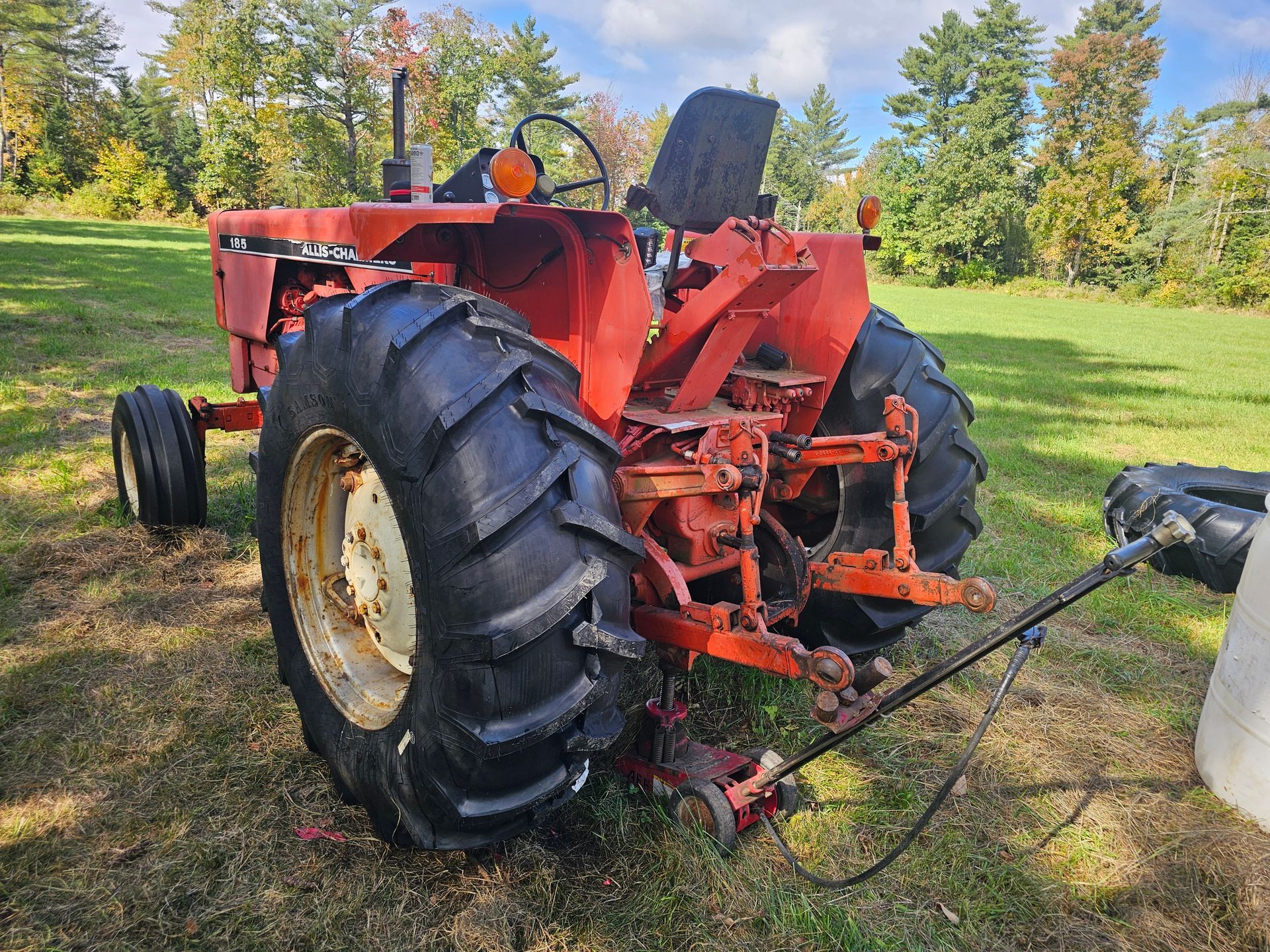 A red tractor is parked in a grassy field.