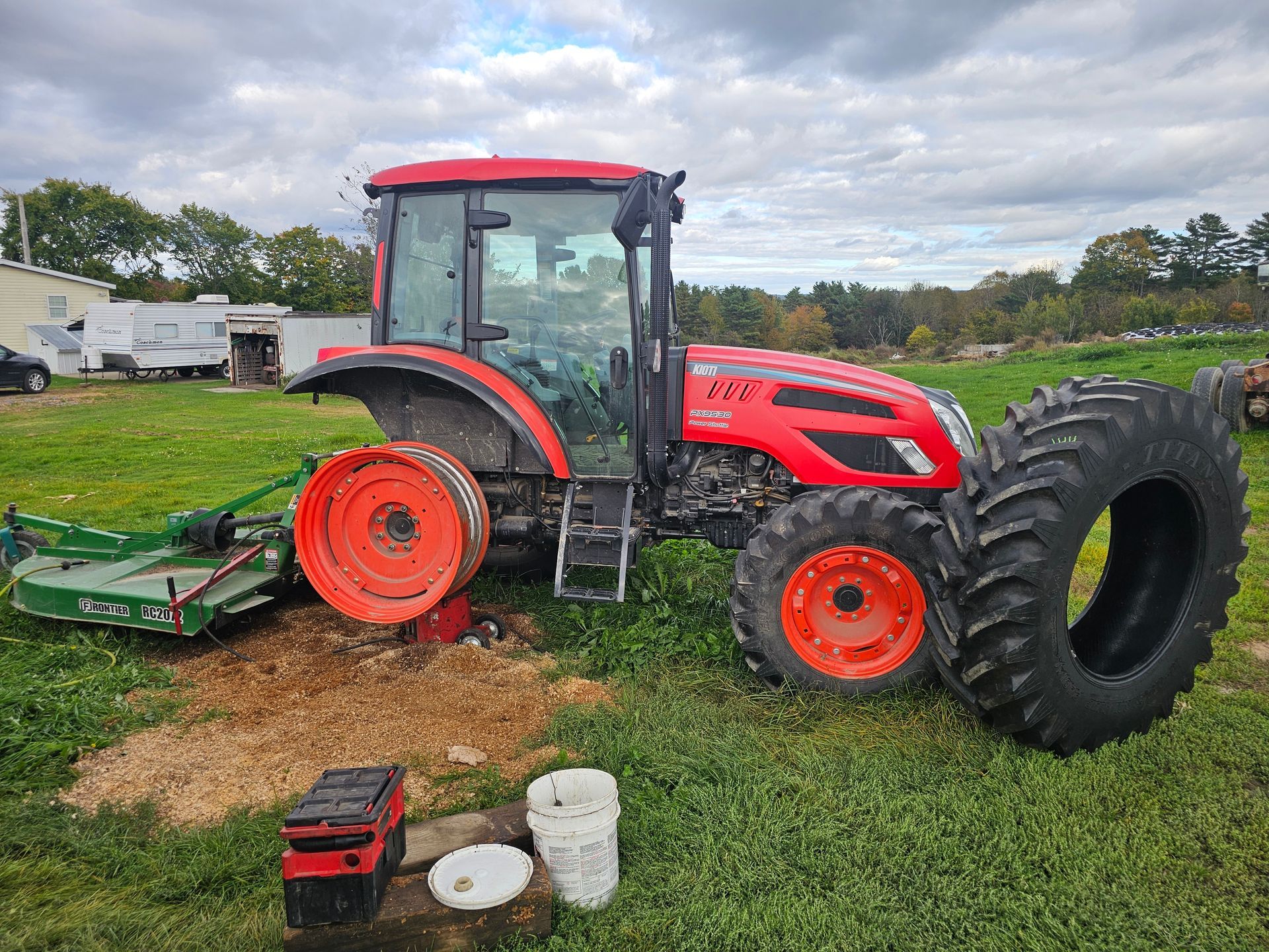 A red and orange tractor is parked in a grassy field.