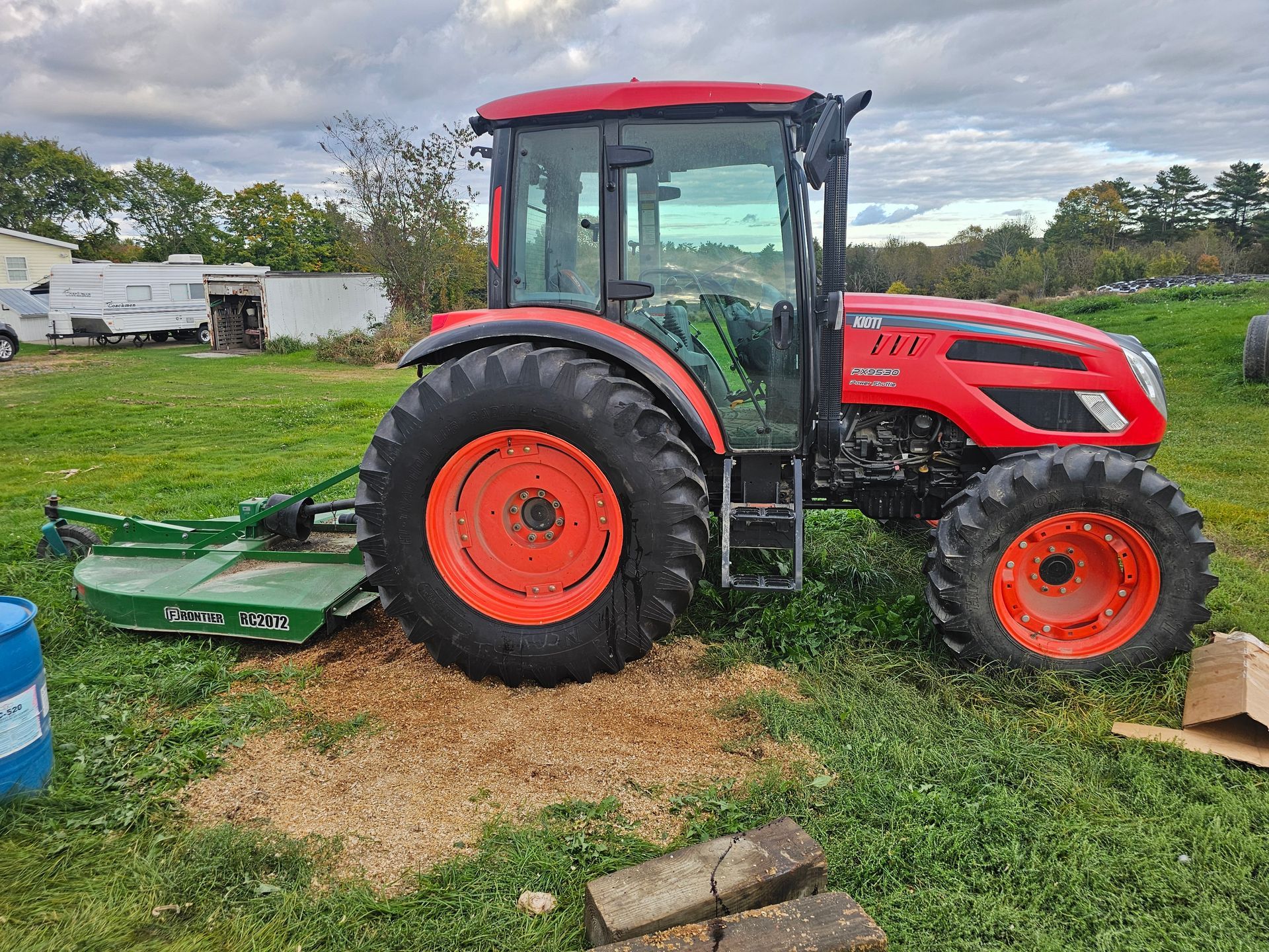 A red and orange tractor is parked in a grassy field.