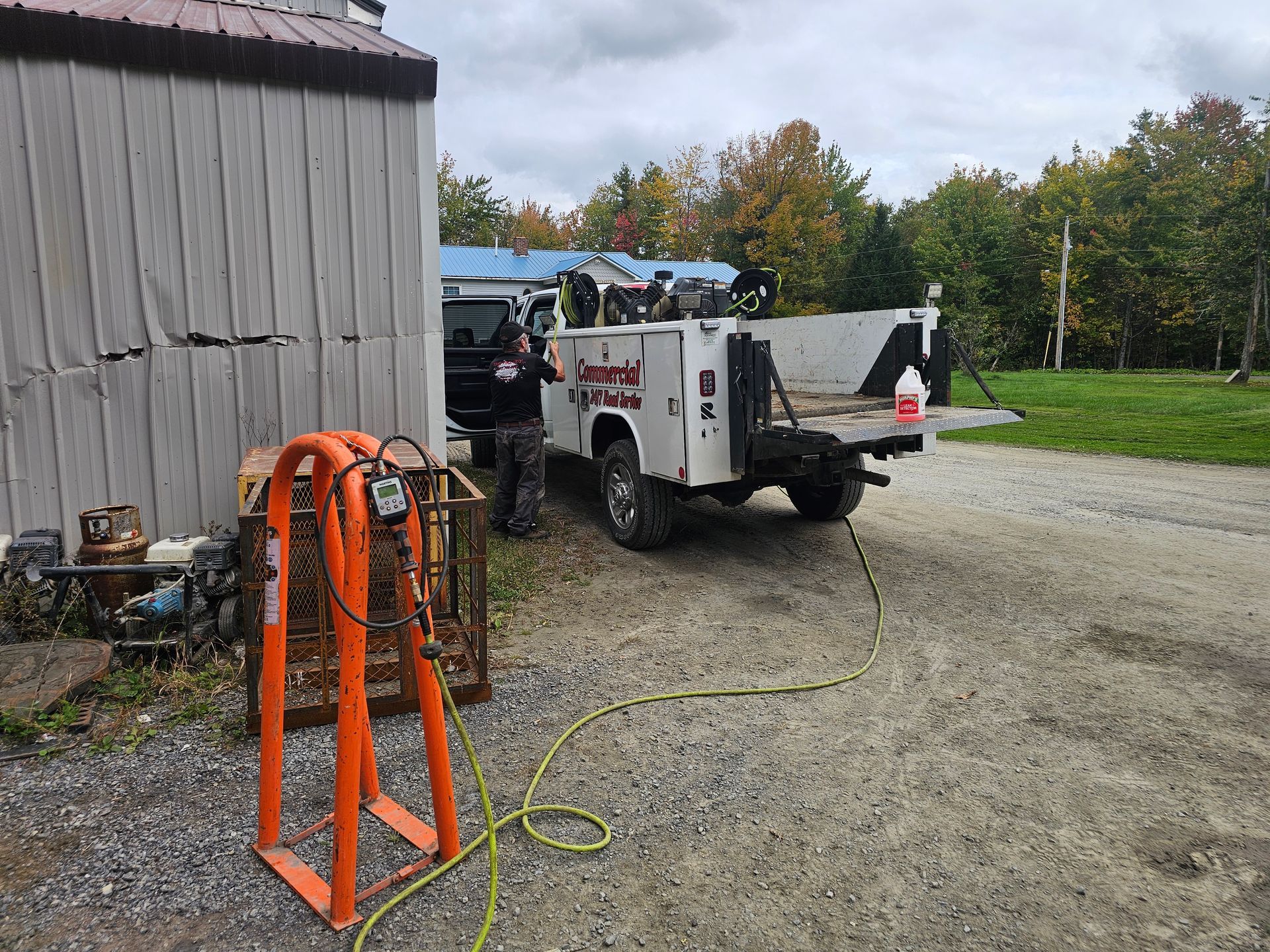 A white truck is parked in a gravel driveway next to a shed.