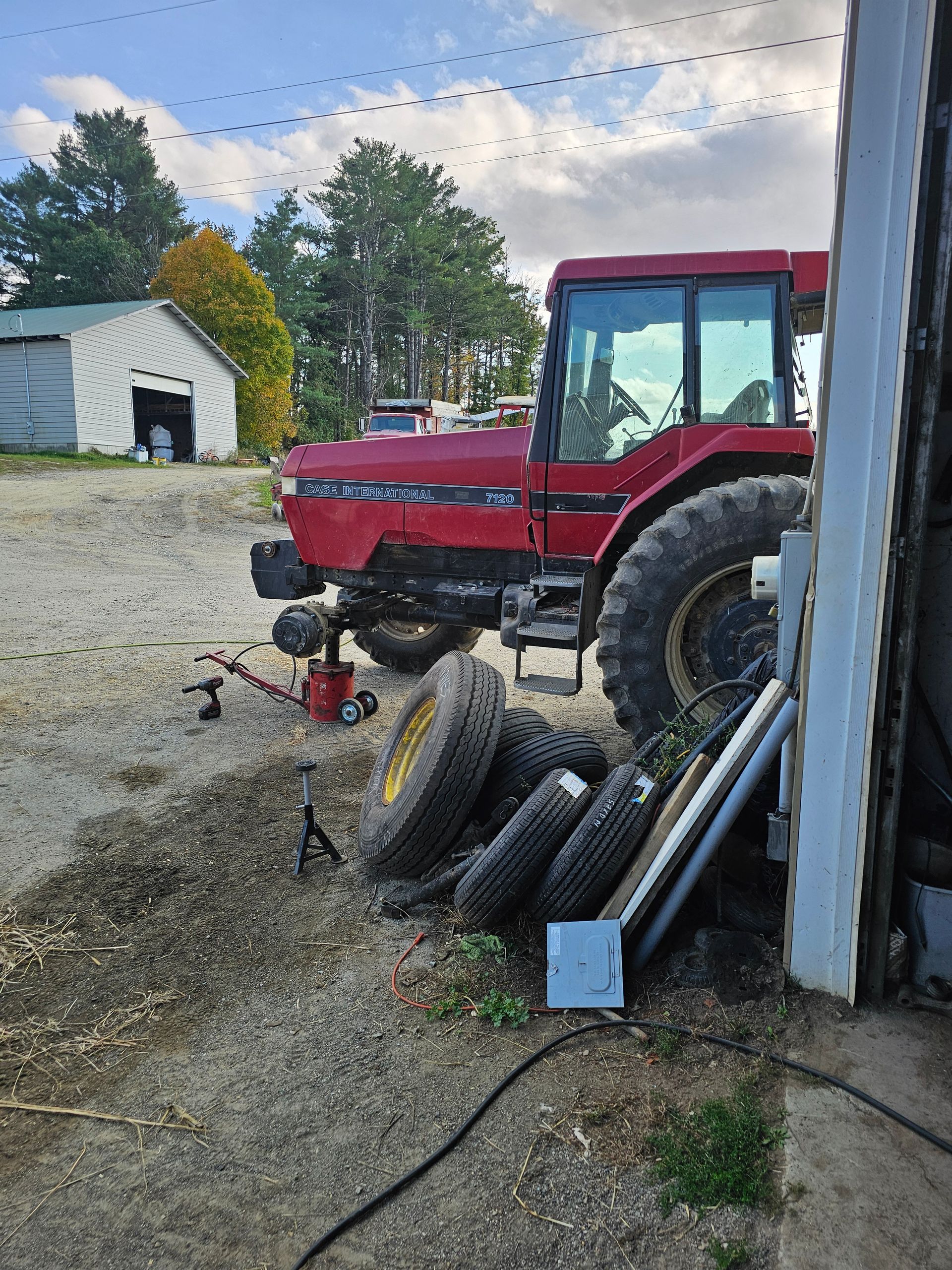 A red tractor is parked next to a pile of tires.