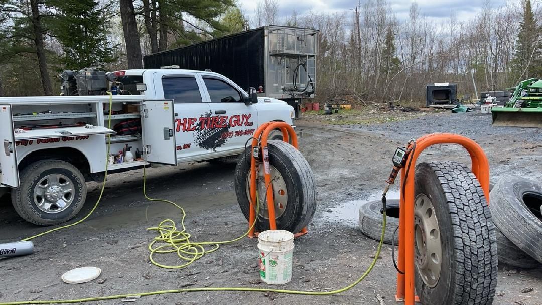 A truck is parked in a parking lot next to a pile of tires.