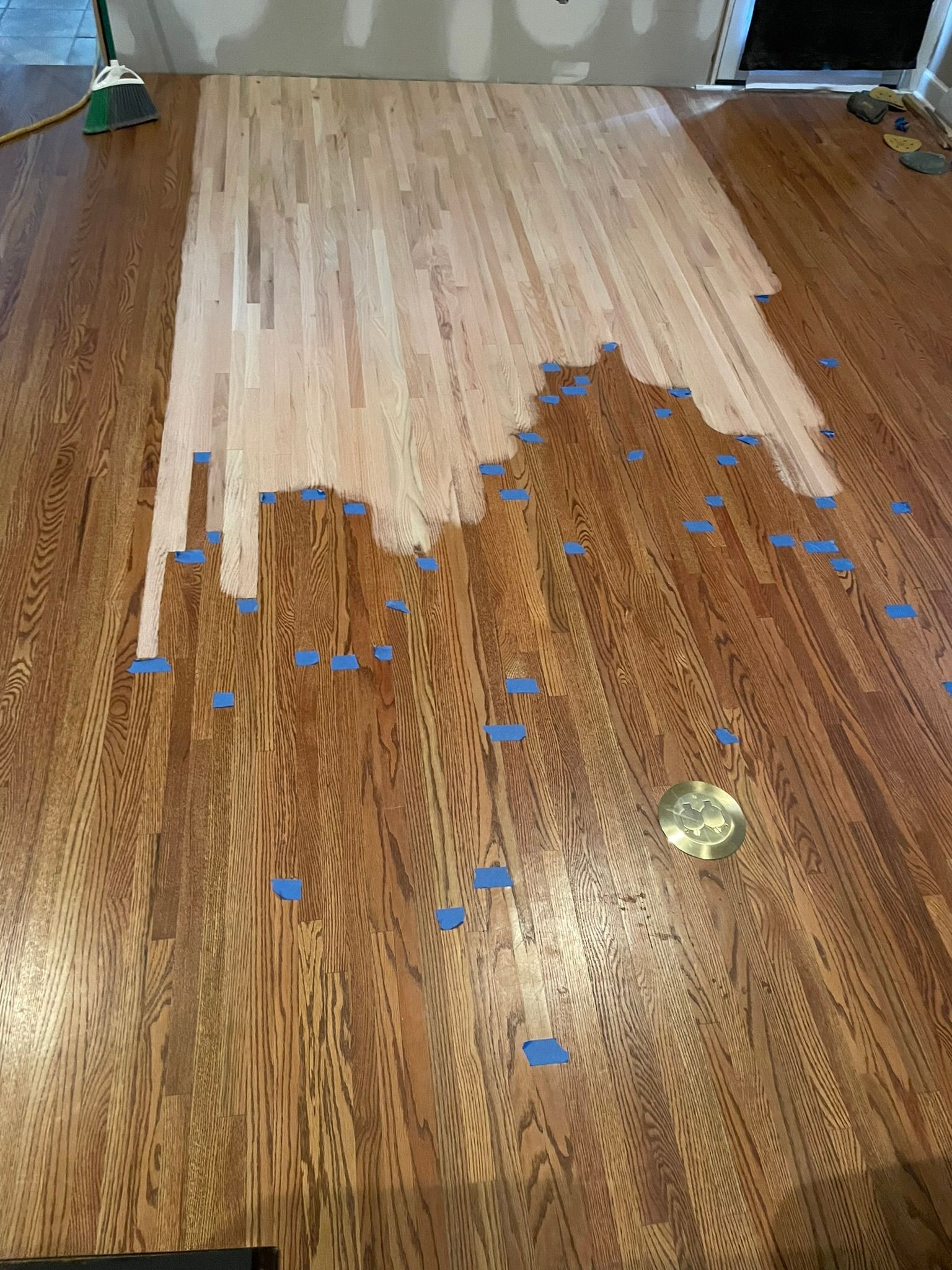 A wooden floor is being painted with blue tape.