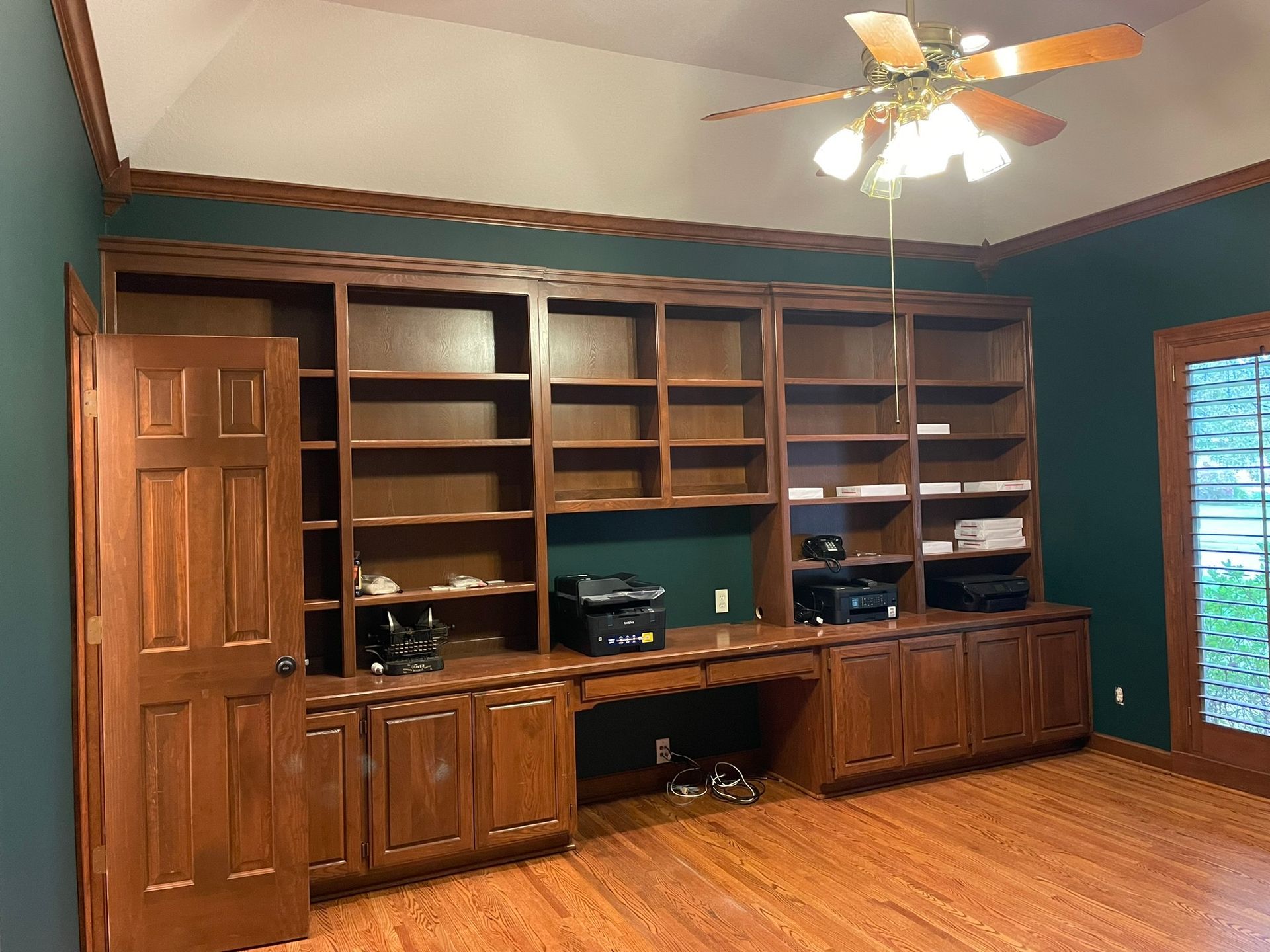 A room with a lot of shelves and a ceiling fan.