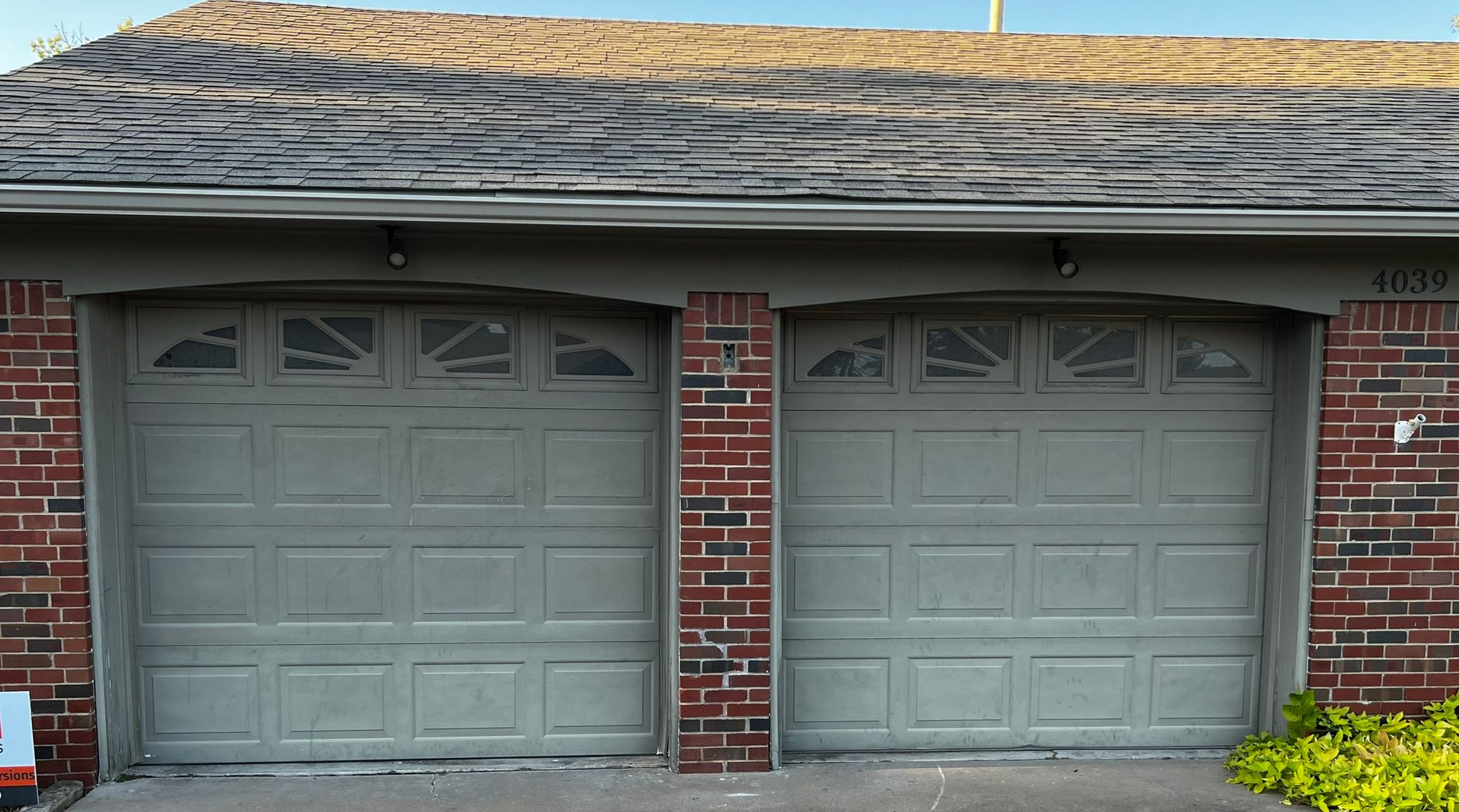 A brick house with two garage doors painted grey