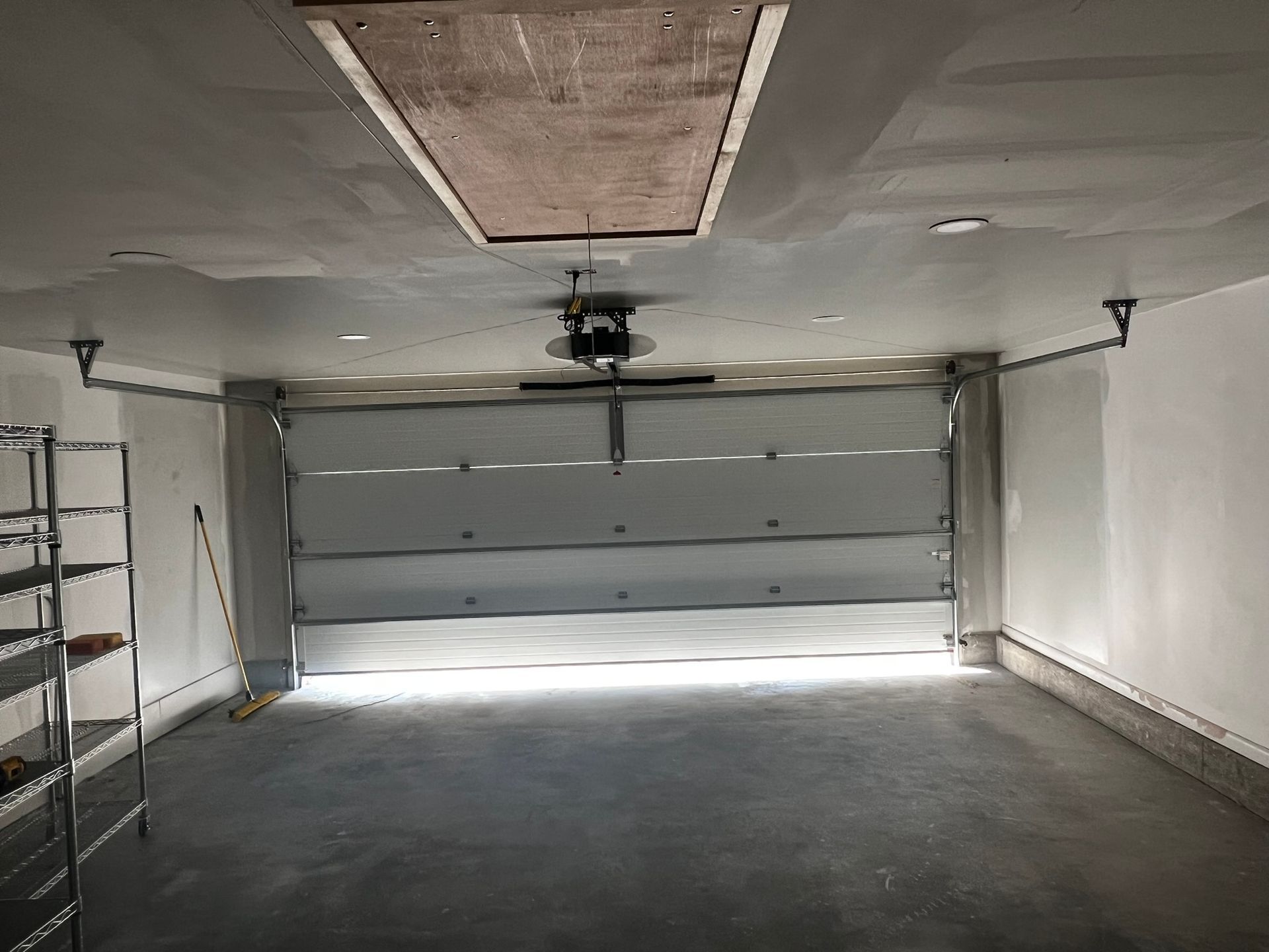 A garage door is partially open viewed from inside. 