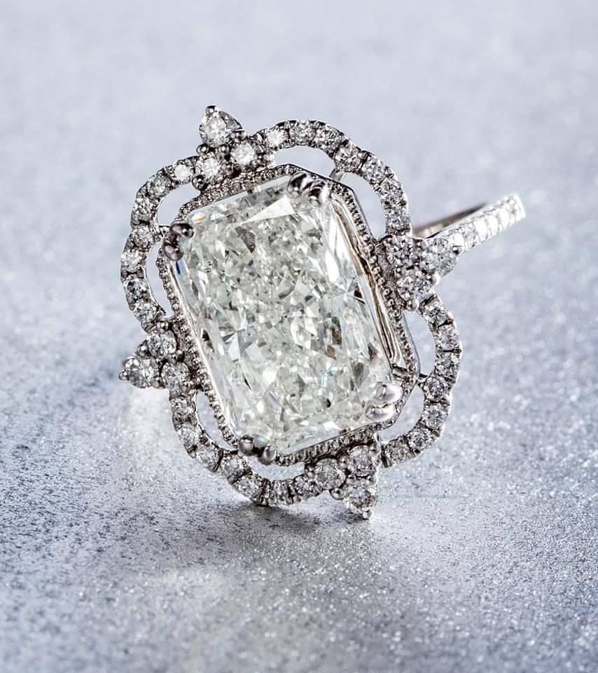 A close up of a diamond ring on a pink surface.
