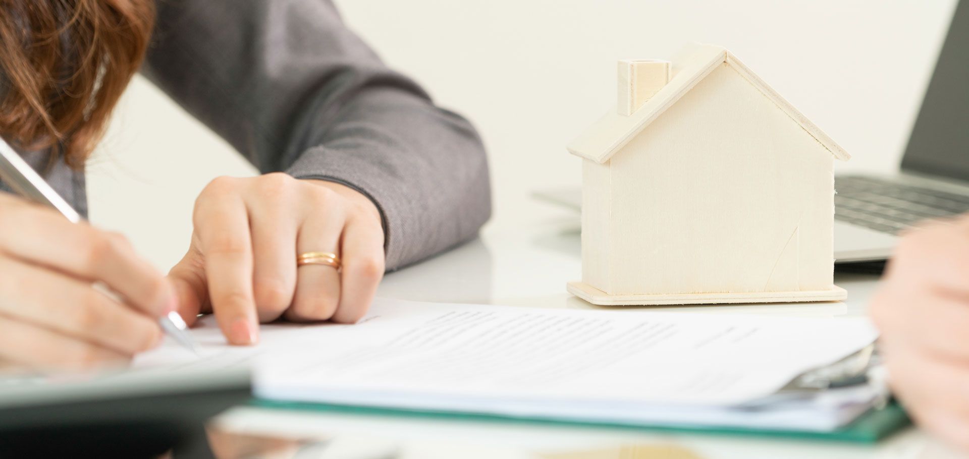 A woman signs a contract with a real estate agent in Medina, OH, assisted by LARIBEE LAW, LLP, an estate lawyer. 