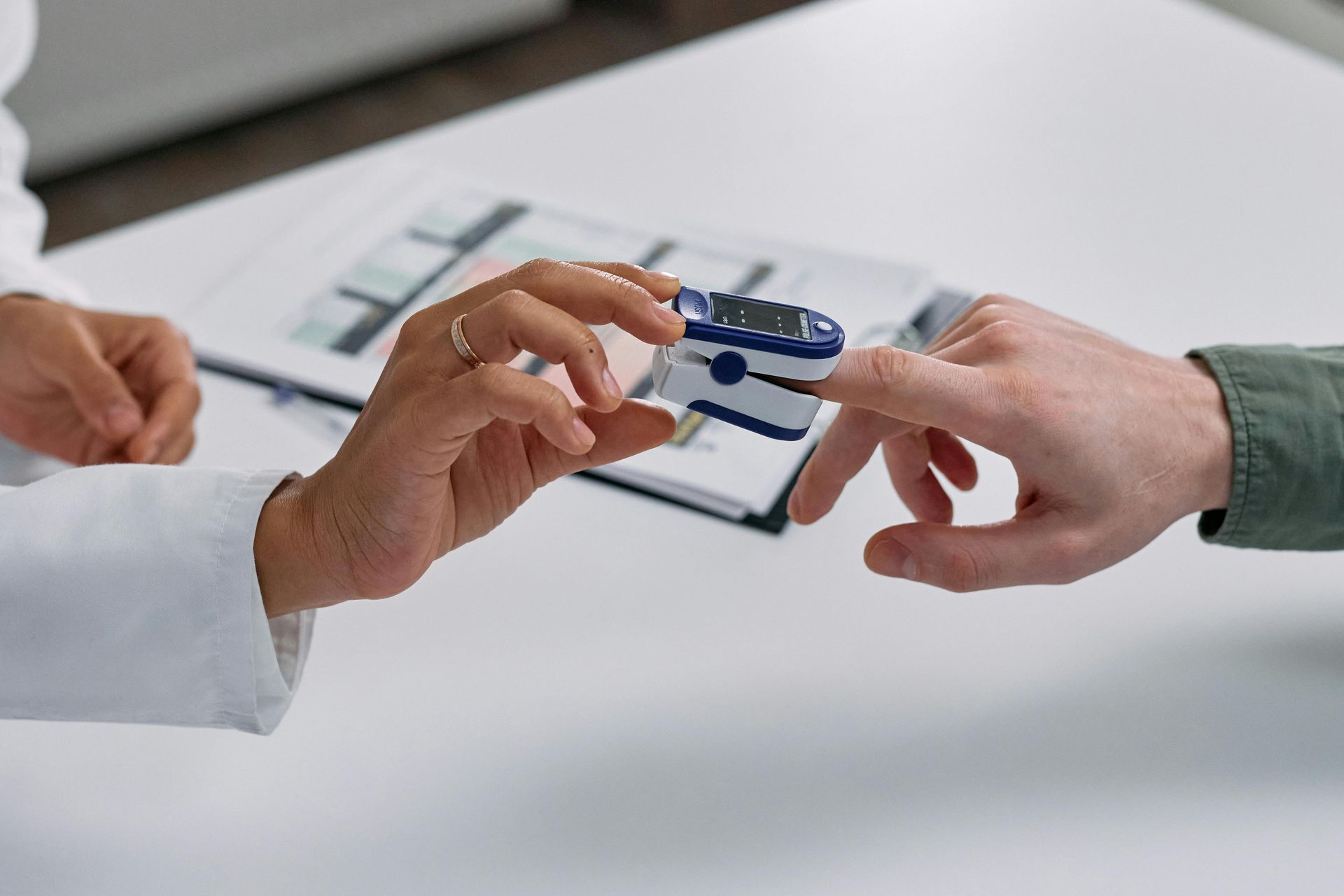 Two hands exchange a blue keycard over a white desk, with a clipboard in the background.