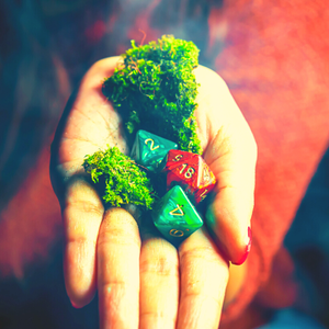 Hand holding green moss and colorful dice.