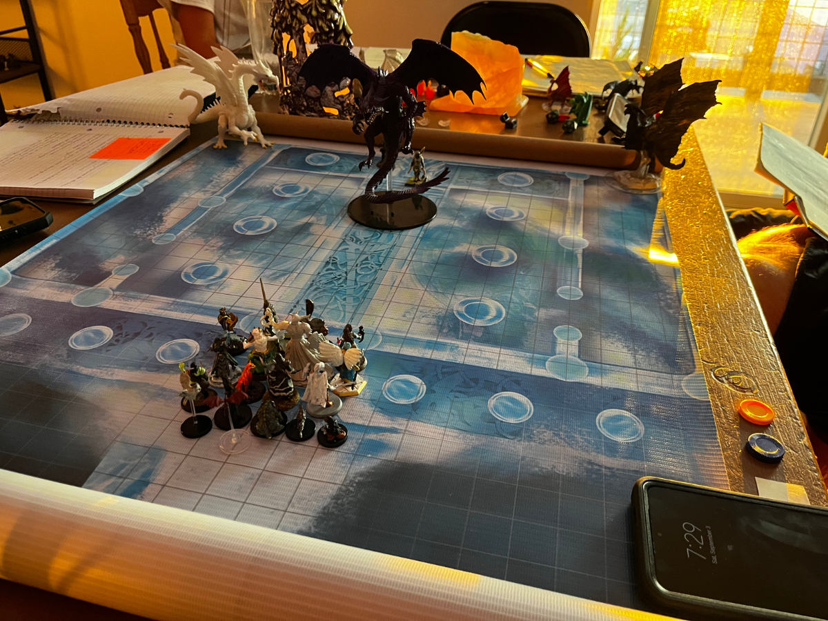 A tabletop role-playing game in progress. Figures of dragons and warriors are arranged on a blue grid map.
