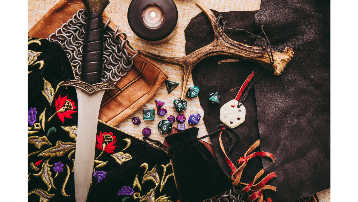 Sword, antlers, dice, candle, and embroidered fabric arranged on a surface.