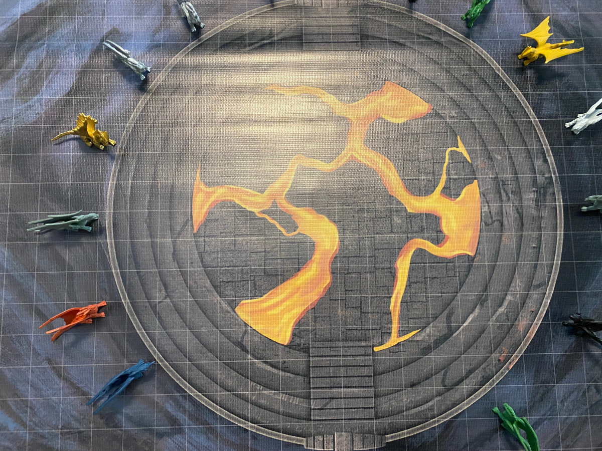 Circular game board with orange lightning graphic, surrounded by toy dragons.