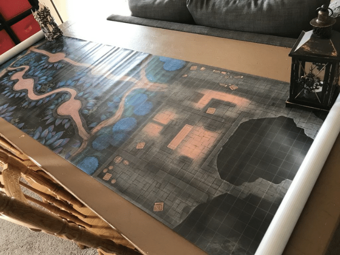 A large game mat with a detailed fantasy map, a lantern, and white border pieces.