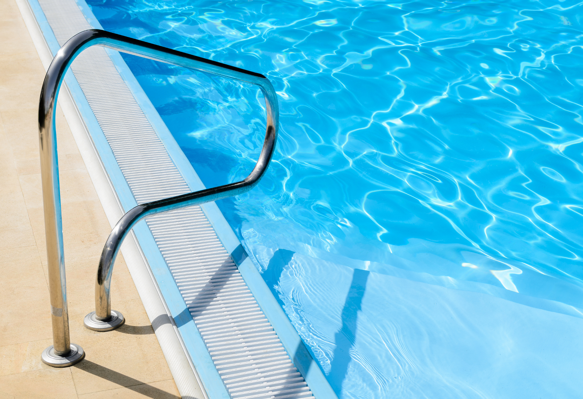 Pool ladder beside clear blue water on a sunny day