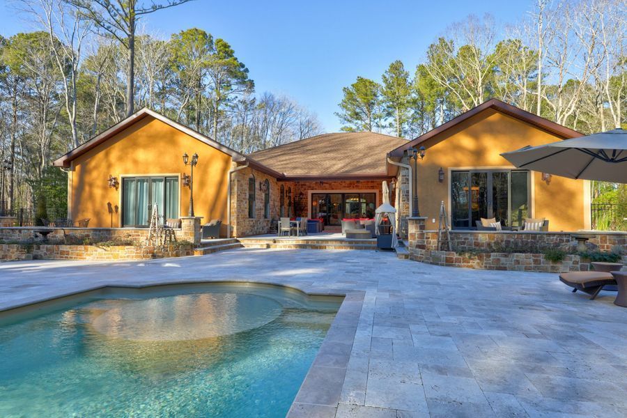 Backyard pool with a home featuring a stucco exterior, stone accents, and a patio with outdoor furniture.