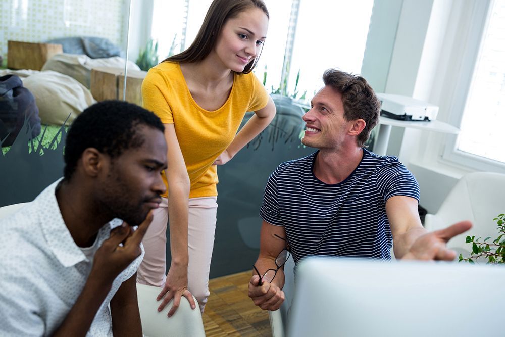 a group of people sitting around a laptop computer