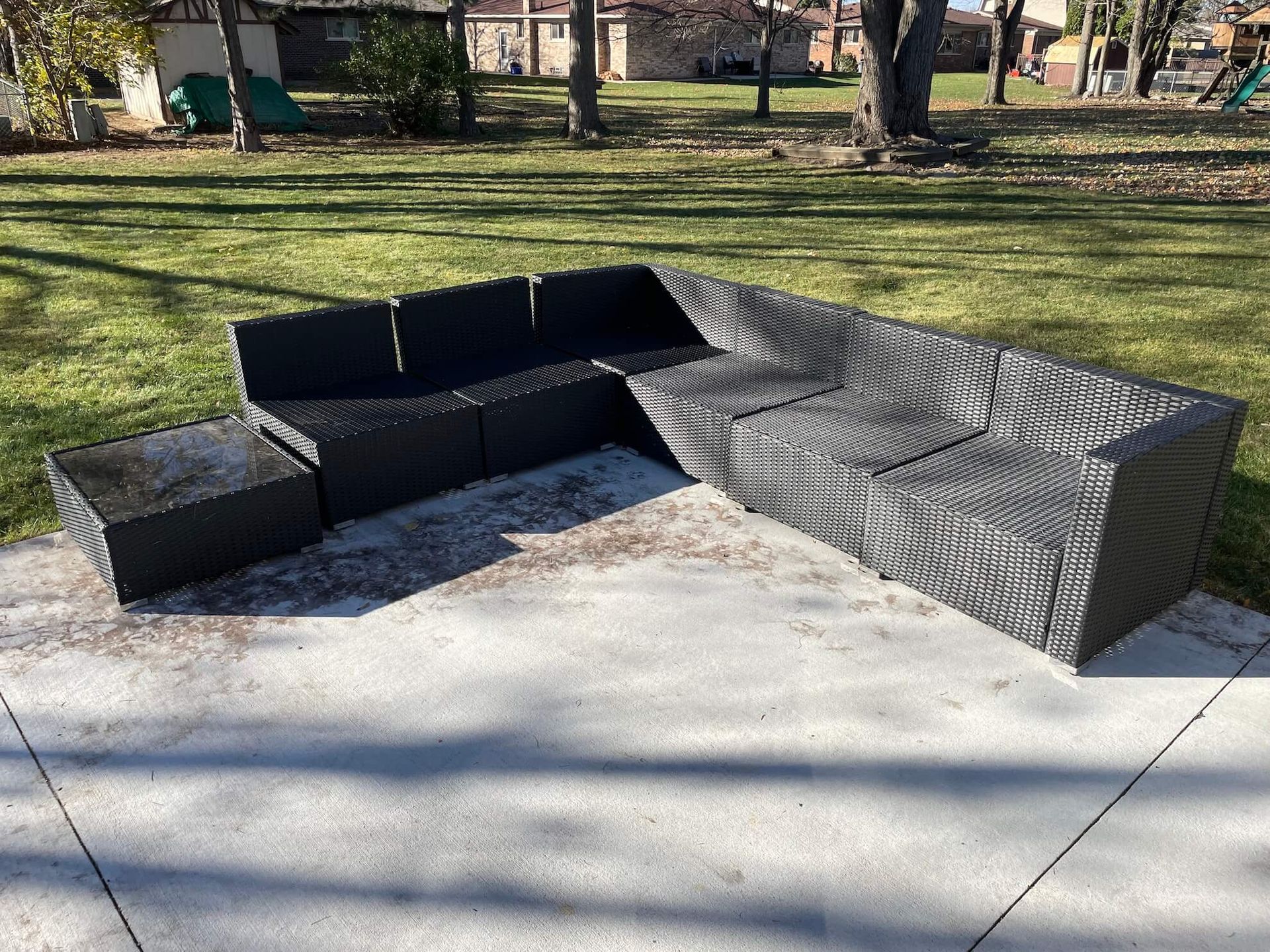 Black outdoor sectional sofa on a concrete patio.