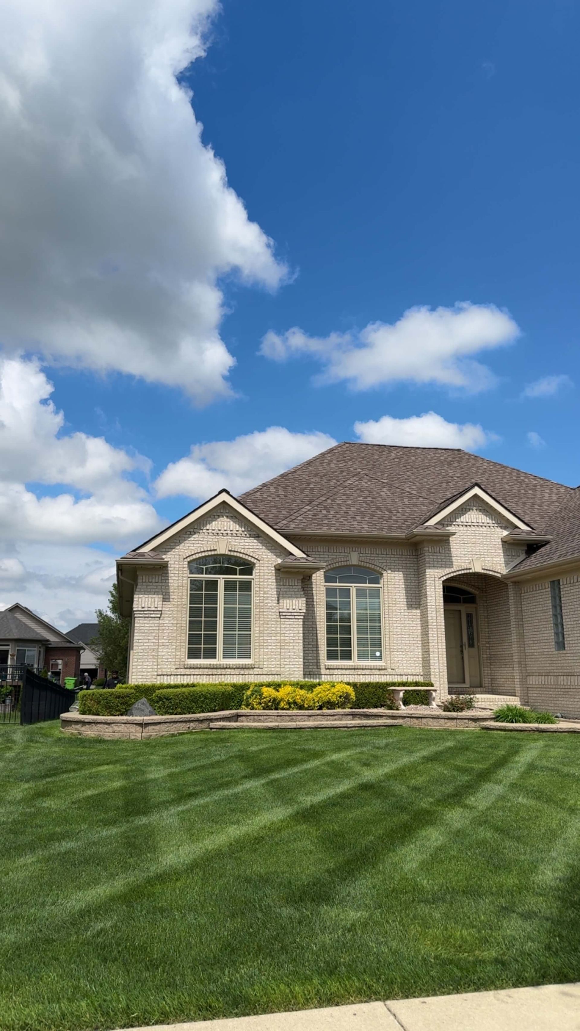 House with manicured lawn under a partly cloudy sky.