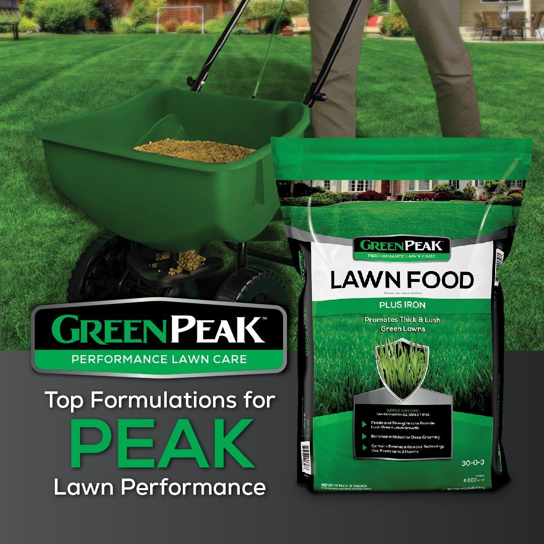 A person is spreading green peak lawn food on a lush green lawn