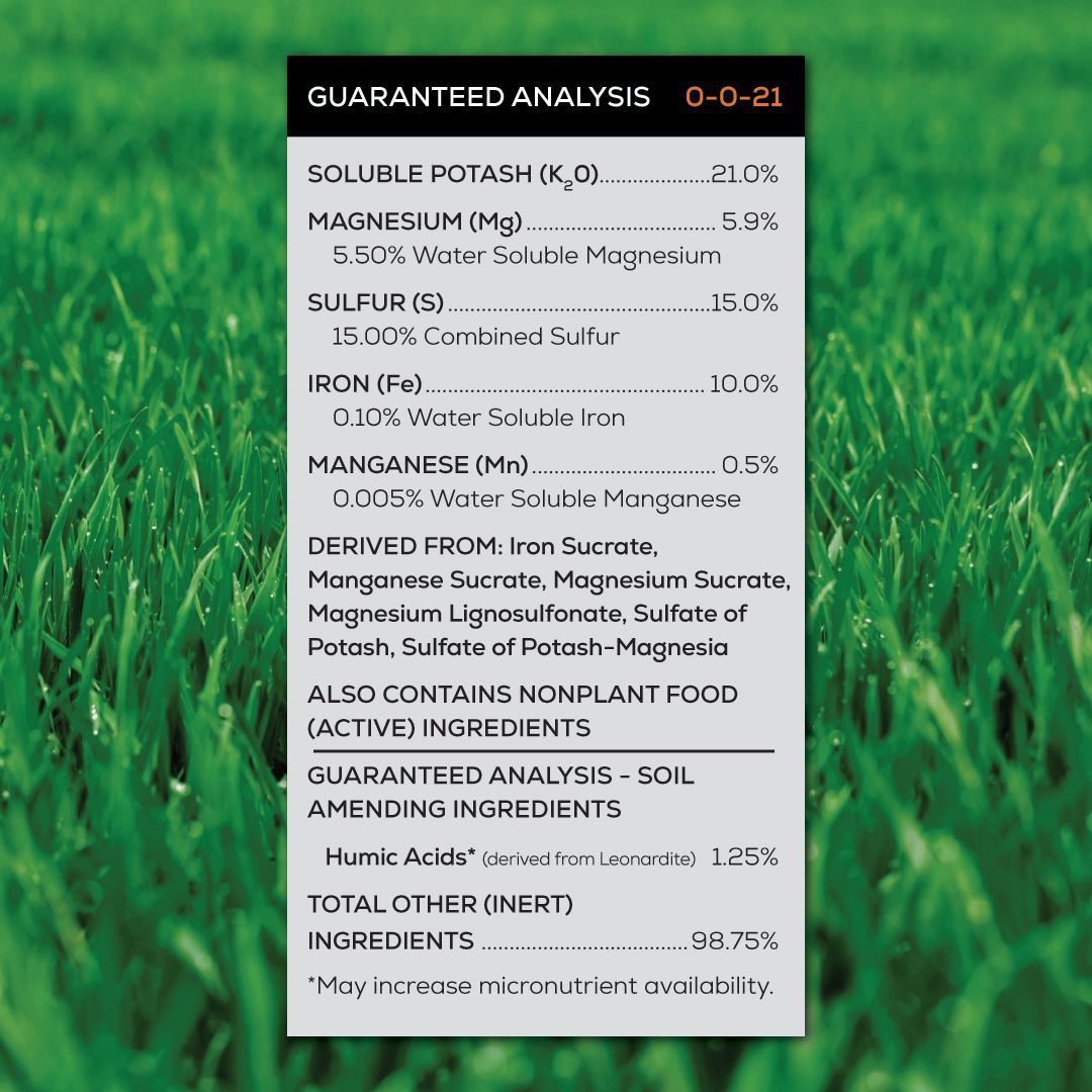 A guaranteed analysis label for lawn strong is sitting on top of a lush green field