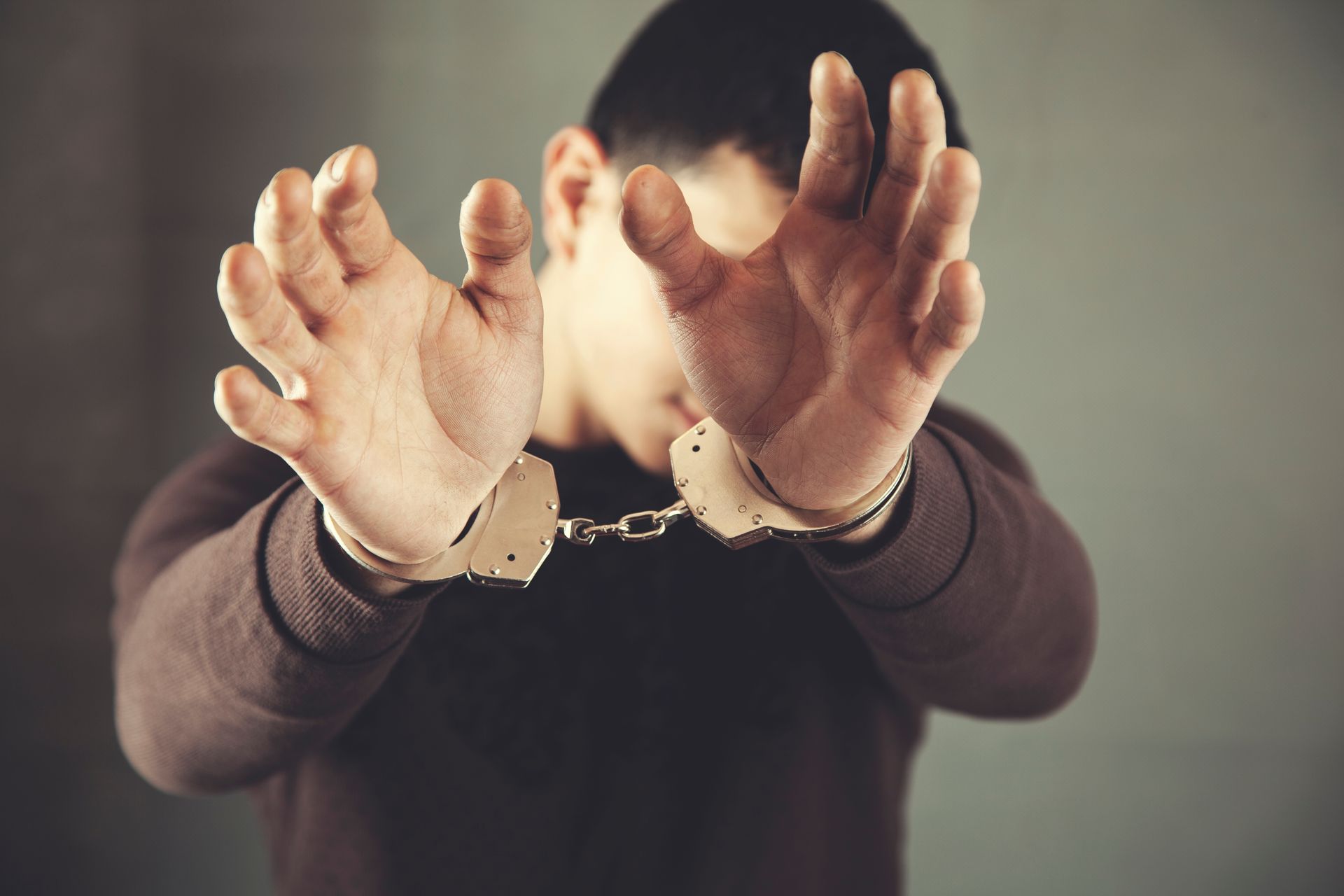 Man in handcuffs, arms outstretched, to symbolize battery charges in Utah.