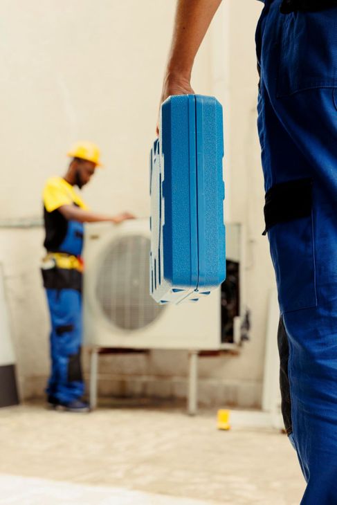 Worker holding blue cleaning tool in a factory, with another worker and large machine in the background
