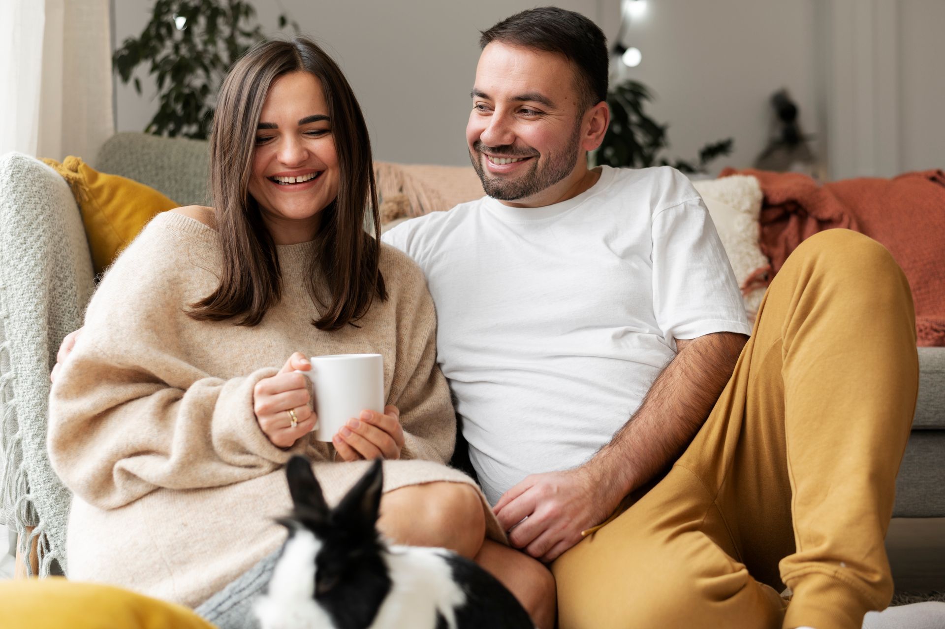 A man and a woman are sitting on a couch with a dog.