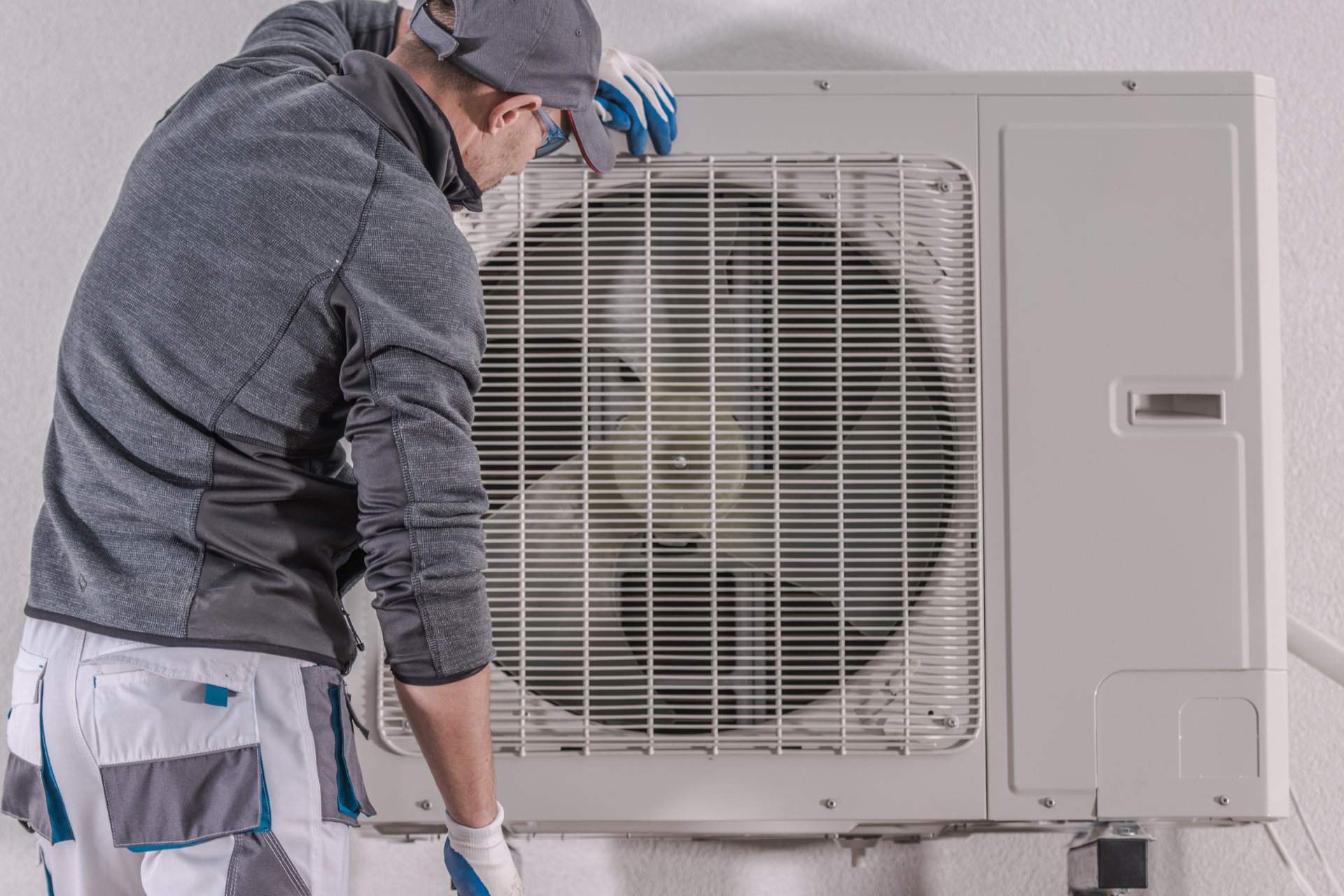 Technician inspecting an outdoor air conditioning unit with the front panel open