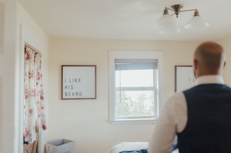 Man in vest, facing away, in a room with a sign saying 
