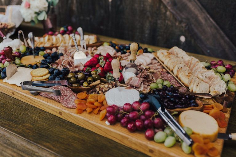 Charcuterie board overflowing with cheeses, fruits, meats, and crackers on a wooden table.