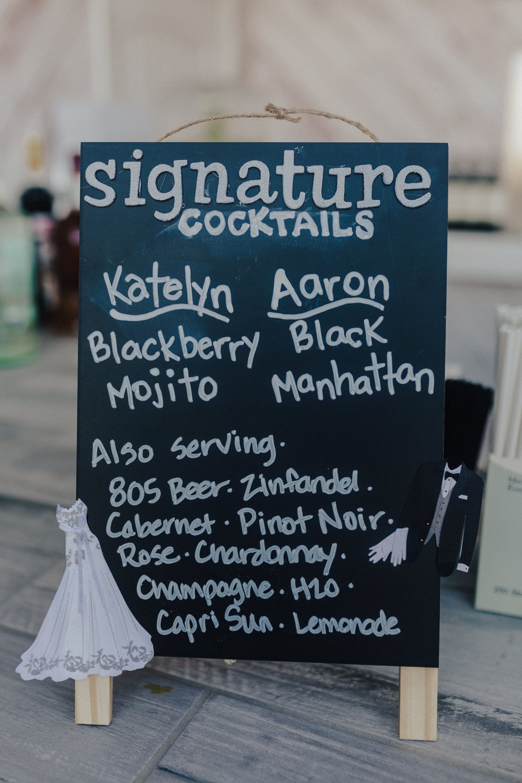 Blackboard sign lists signature cocktails for Katelyn and Aaron's wedding: Blackberry Mojito, Black Manhattan, and other drinks.