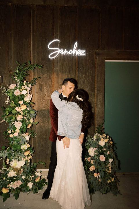 Couple kissing at wedding, under neon 