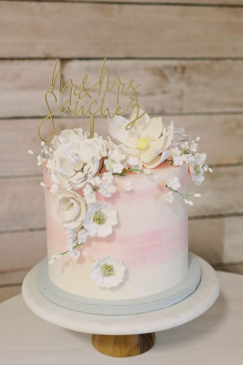 Wedding cake with white and pink ombre icing, floral decorations, and a 