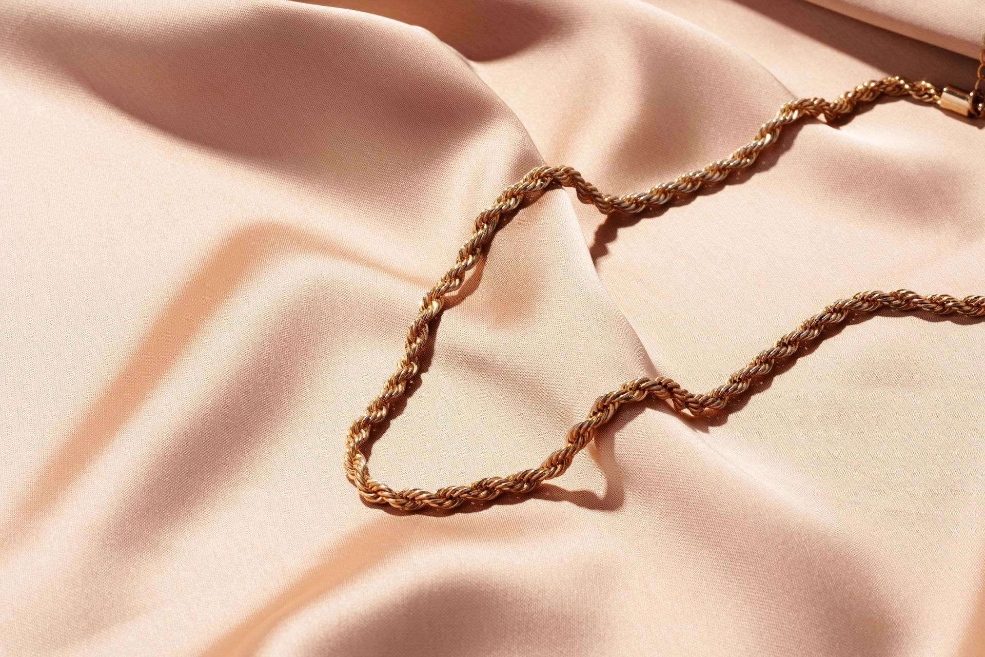 Una catena d'oro è adagiata su un panno rosa.