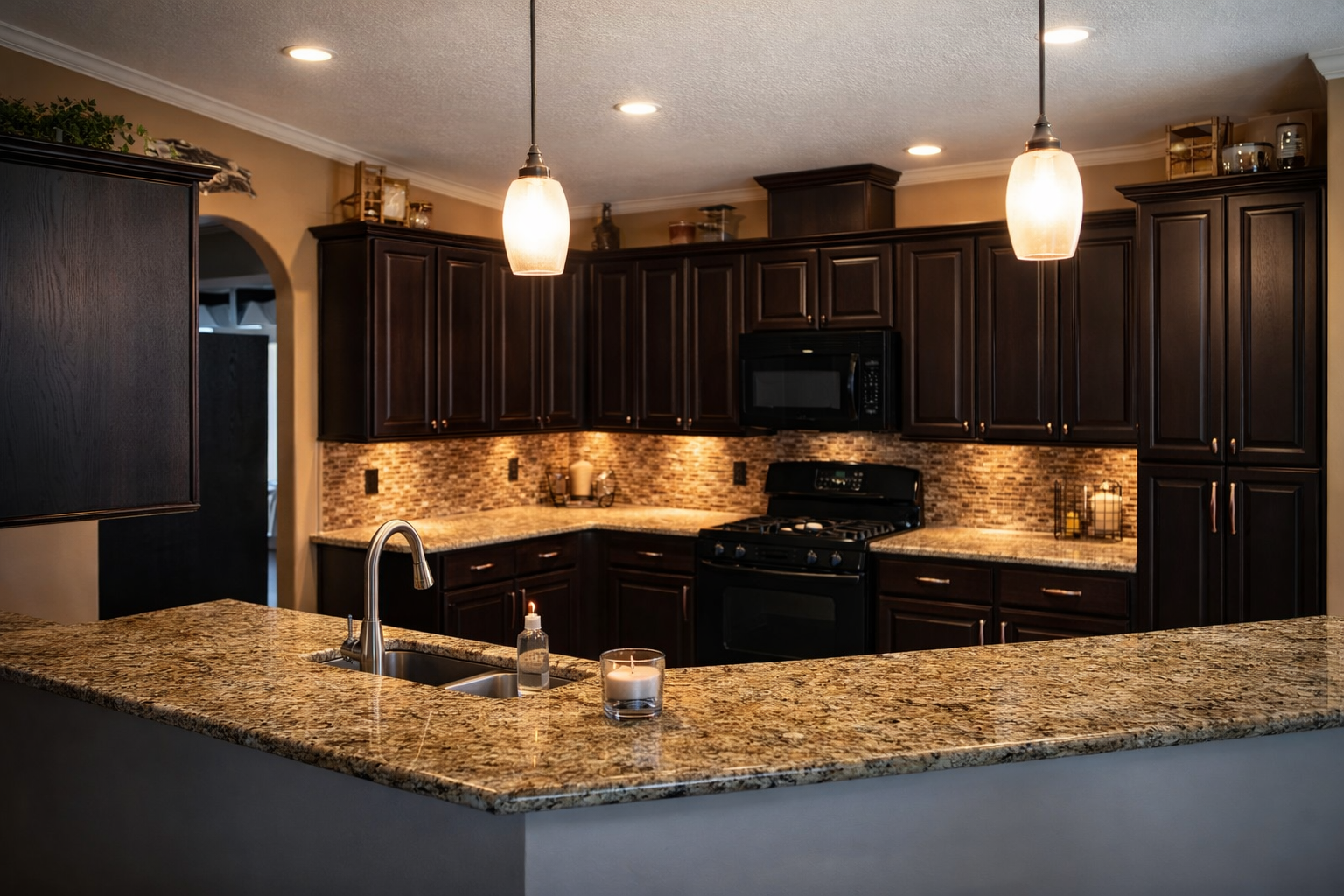 Kitchen with dark brown cabinets, light granite countertops, and two pendant lights.