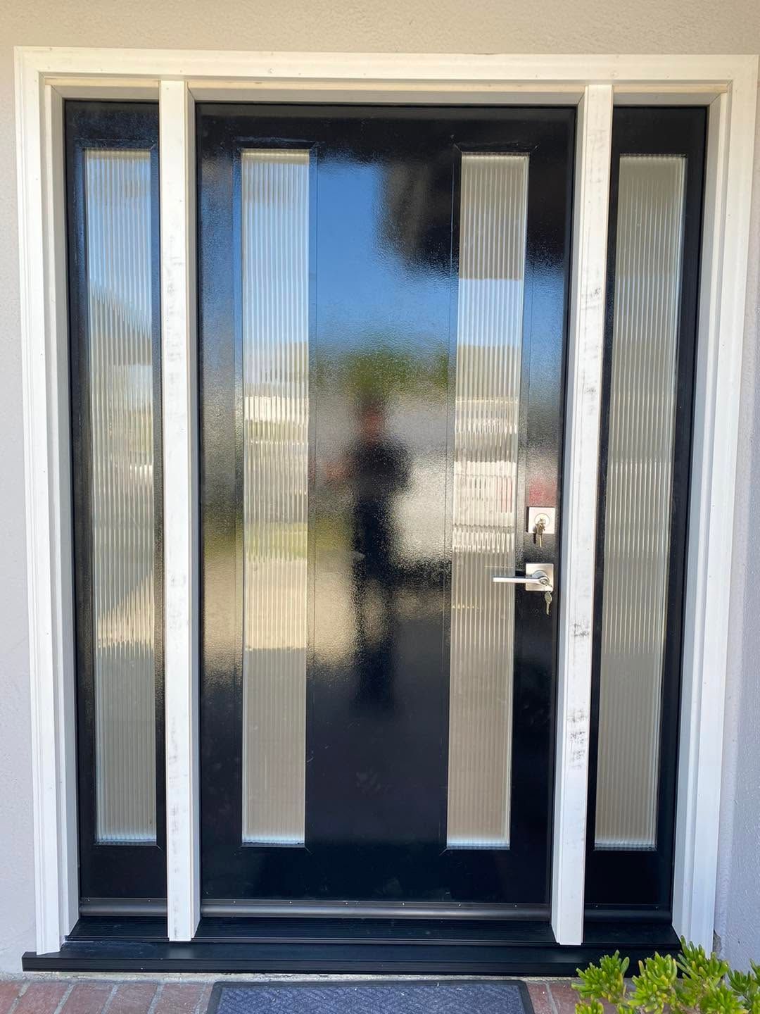 Black front door with frosted glass sidelights and silver handle on a house entrance