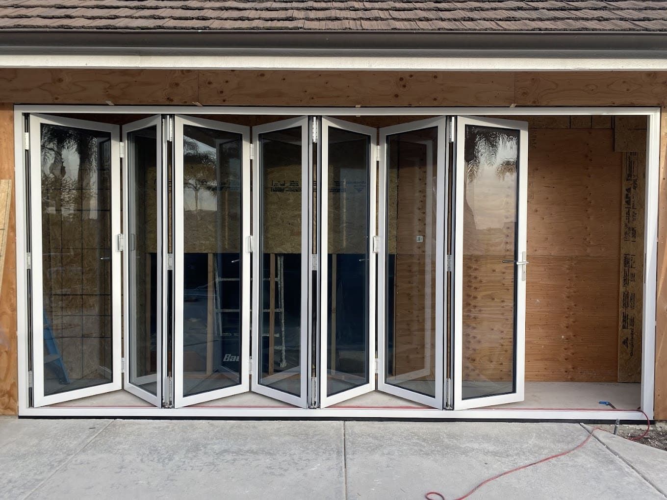 Open folding glass wall of white-framed doors in a brick building facade