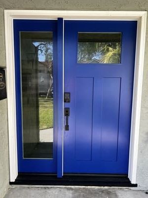 Blue front door with narrow side window and small upper window on a house exterior