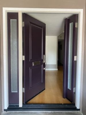 Open front door with dark purple double doors, revealing a light wood-floored interior.