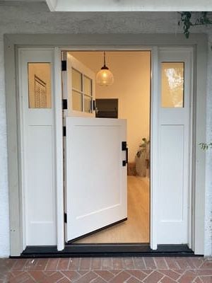 Open front door with white sidelights leading into a bright entryway with a hanging globe light.