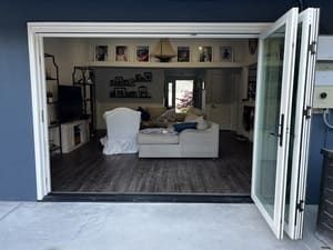 Open patio doors to a blue-walled living room with a white sofa and wood floor