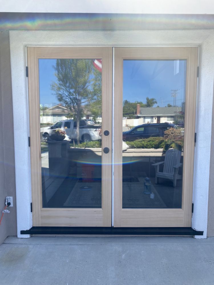 Double glass entrance doors with white trim and reflections of an outdoor parking area