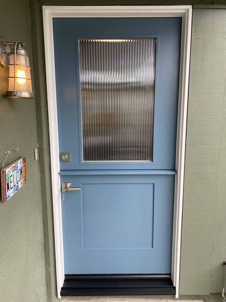 Blue exterior door with frosted glass window and silver handle, set in a light green wall.