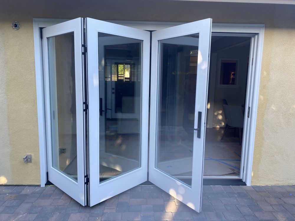 White folding glass doors open into a building entrance with a beige wall.