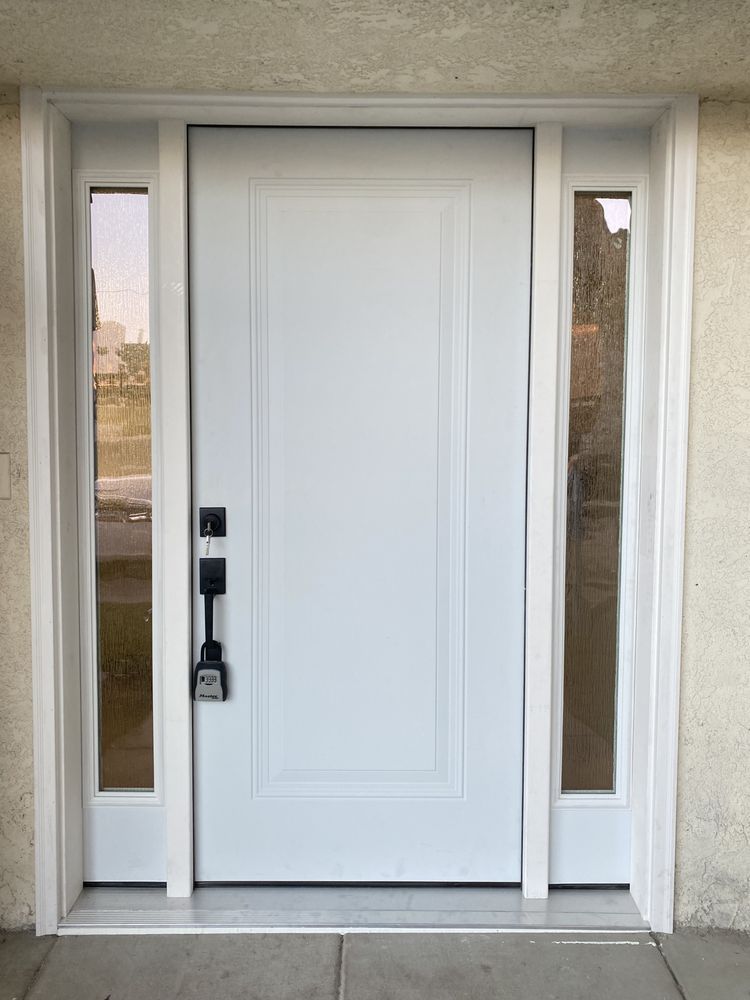 Front entrance with a white door, sidelights, and a black lock on a stucco exterior wall.