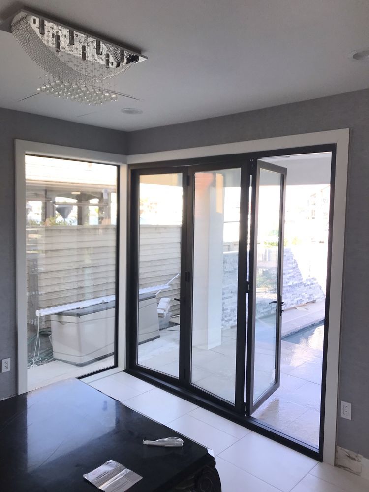 Modern room with dark floors, gray walls, sliding glass doors, and a crystal ceiling light.